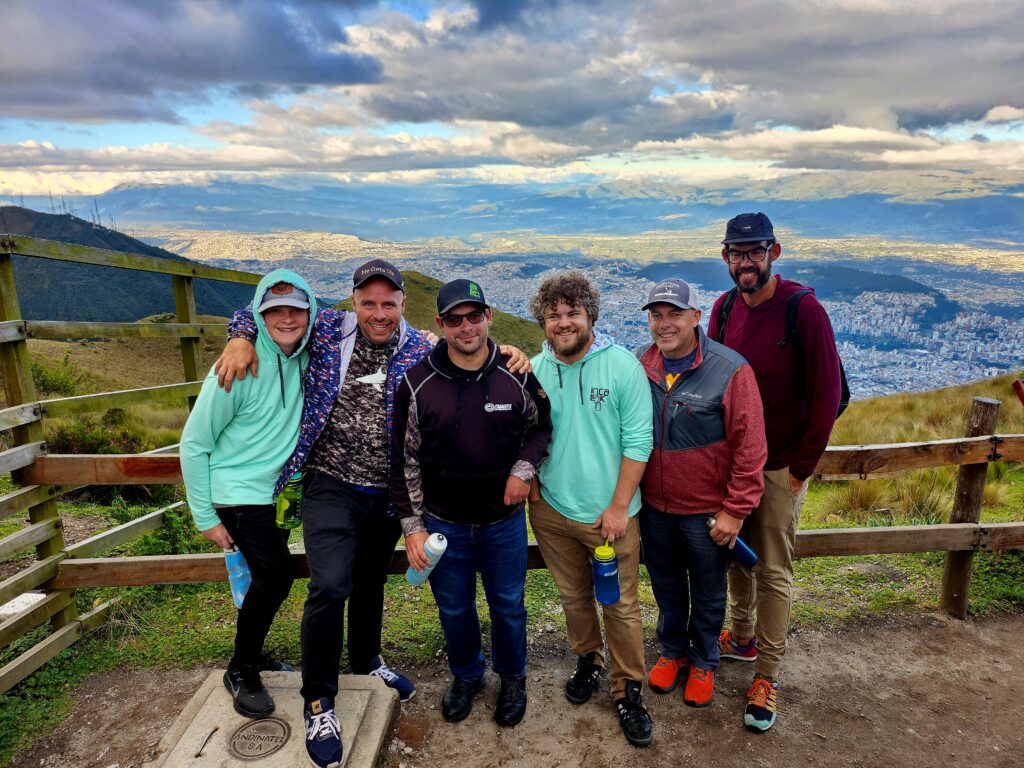 Six people from the Ends gravel cycling tour standing by a fence at the top of a mountain.