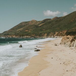 View of green hill shoreline from a sand beach. Original public domain image from Wikimedia Commons